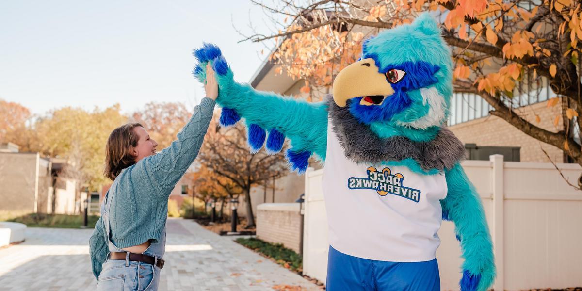 Student high-fiving AACC mascot, Swoop.